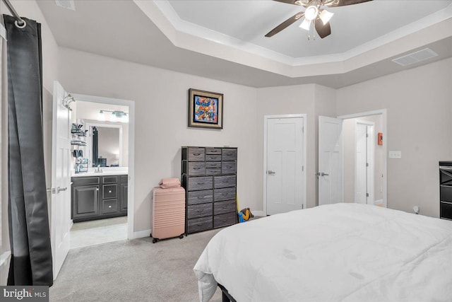 bedroom featuring light carpet, visible vents, a raised ceiling, and connected bathroom