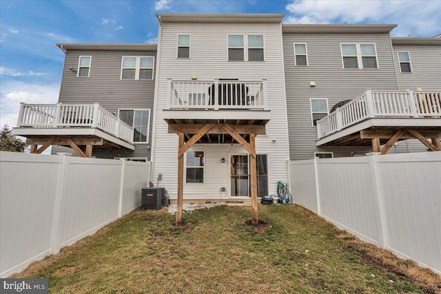 rear view of house with a fenced backyard, central AC, a deck, and a lawn