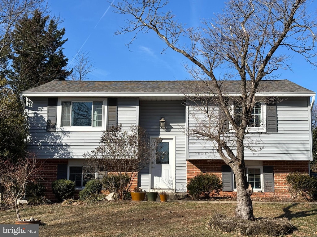 split foyer home with brick siding and a front lawn