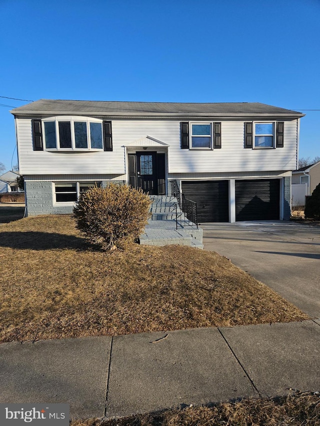 bi-level home featuring concrete driveway and an attached garage