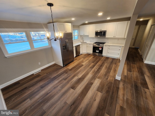 kitchen with white cabinets, decorative light fixtures, stainless steel appliances, light countertops, and a sink