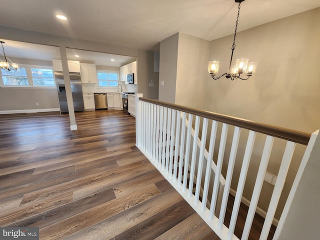 stairway with baseboards, recessed lighting, wood finished floors, and an inviting chandelier