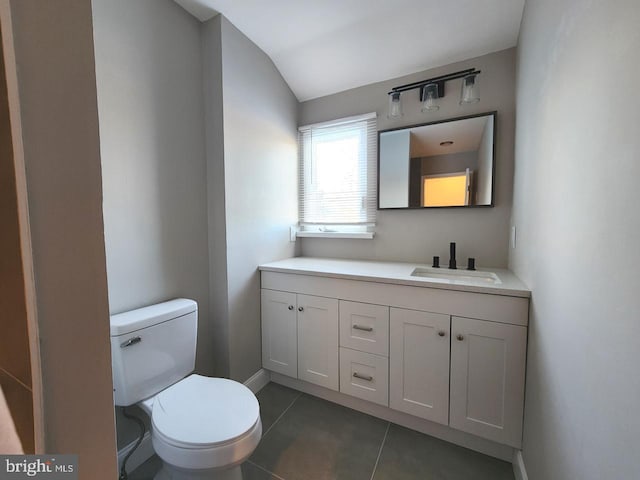 bathroom featuring tile patterned flooring, toilet, vanity, baseboards, and vaulted ceiling