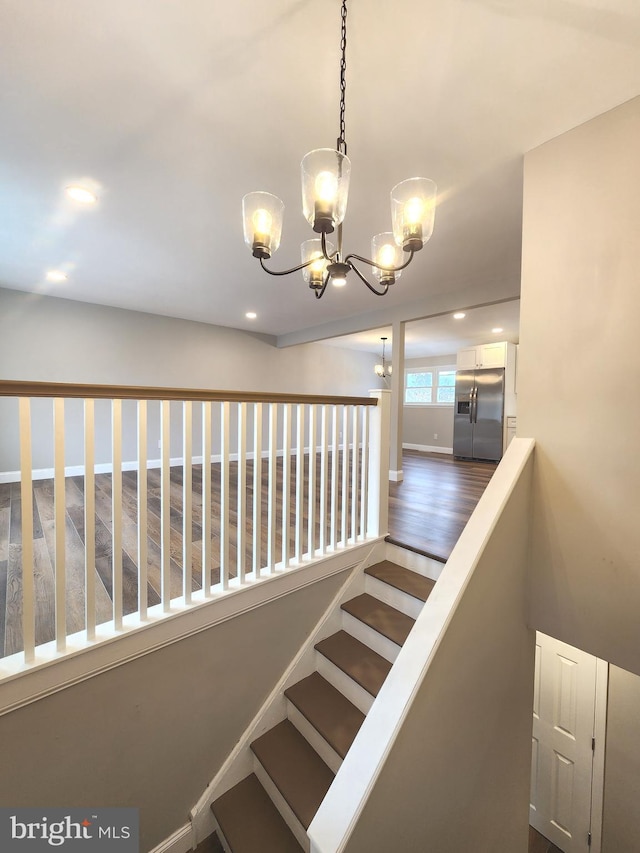 stairs featuring baseboards, recessed lighting, wood finished floors, and a notable chandelier