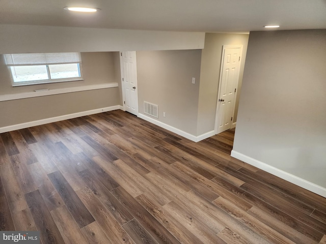 unfurnished room featuring dark wood-style flooring, visible vents, and baseboards