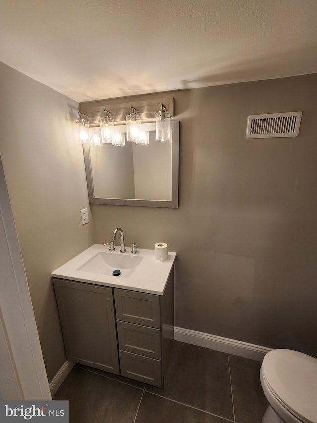 bathroom featuring tile patterned flooring, toilet, vanity, visible vents, and baseboards