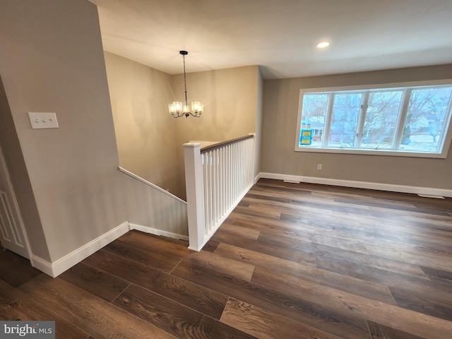 empty room with a notable chandelier, baseboards, dark wood-style flooring, and recessed lighting