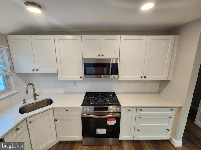 kitchen with stainless steel appliances, light countertops, decorative backsplash, white cabinetry, and a sink