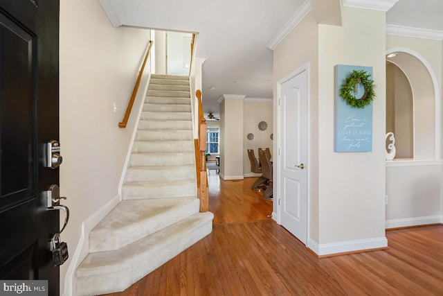 entryway featuring ornamental molding, stairway, wood finished floors, and baseboards