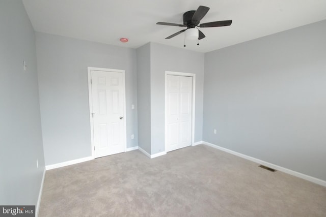 unfurnished bedroom featuring ceiling fan, light colored carpet, visible vents, baseboards, and a closet