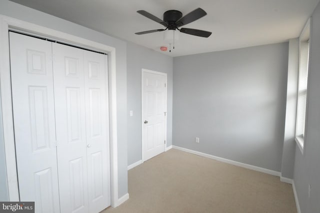 unfurnished bedroom with ceiling fan, baseboards, a closet, and light colored carpet