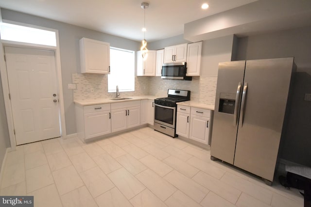 kitchen with white cabinets, a sink, stainless steel appliances, and light countertops