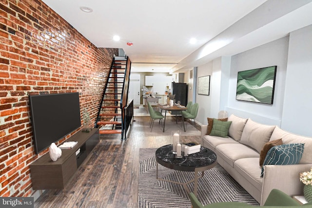 living area with dark wood-type flooring, recessed lighting, baseboards, and brick wall