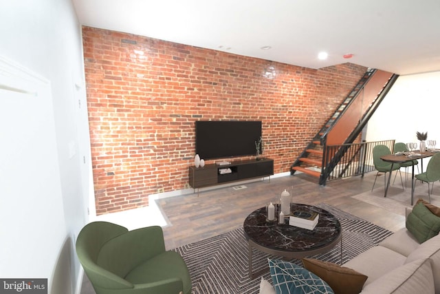 living area featuring brick wall, stairway, wood finished floors, and recessed lighting