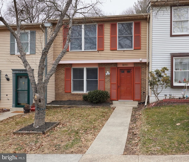 townhome / multi-family property featuring a front lawn and brick siding