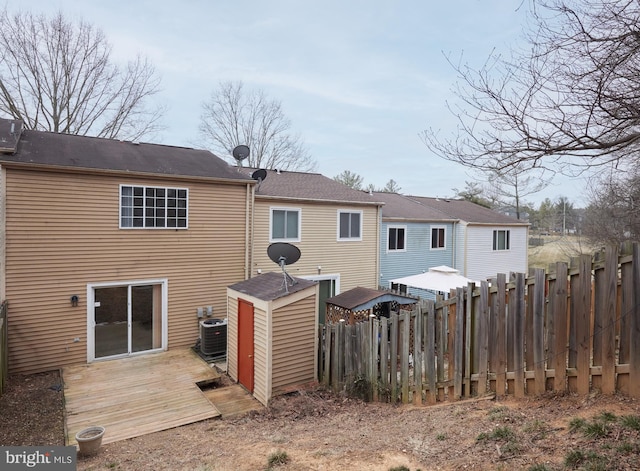 rear view of house with cooling unit, fence, and a wooden deck