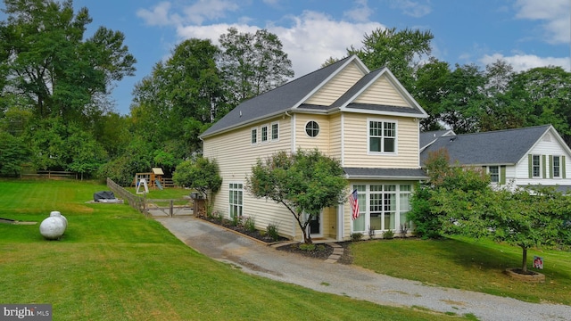 view of side of property featuring a playground, a lawn, and driveway