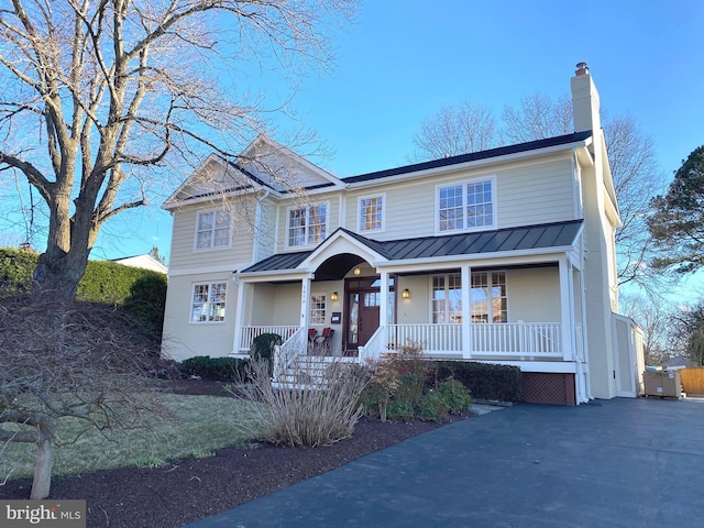 view of front of house featuring metal roof, a standing seam roof, a chimney, and a porch