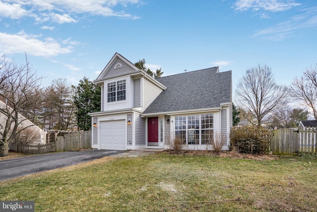 traditional-style house featuring aphalt driveway, a front lawn, and fence