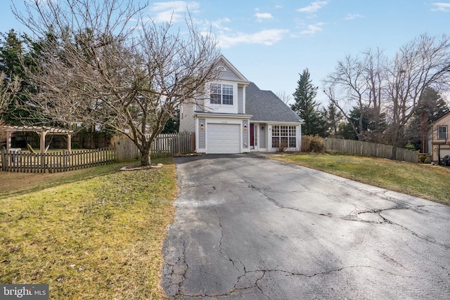 view of front of home featuring a front lawn, an attached garage, fence private yard, and aphalt driveway