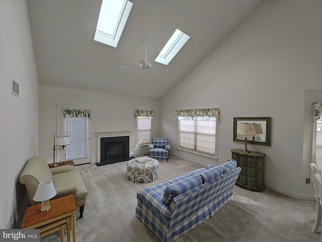 living room with carpet floors, a skylight, a fireplace with flush hearth, and visible vents