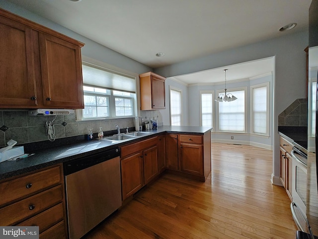 kitchen with a sink, stainless steel dishwasher, brown cabinets, dark countertops, and pendant lighting