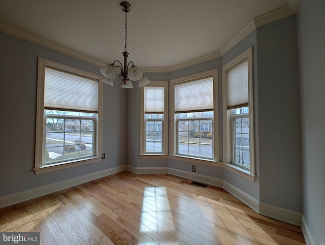 empty room featuring crown molding, light wood-type flooring, visible vents, and a notable chandelier