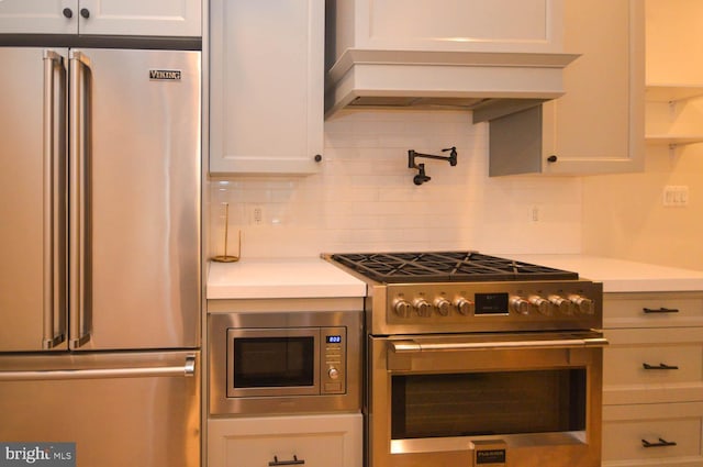 kitchen featuring white cabinets, decorative backsplash, premium appliances, custom exhaust hood, and light countertops