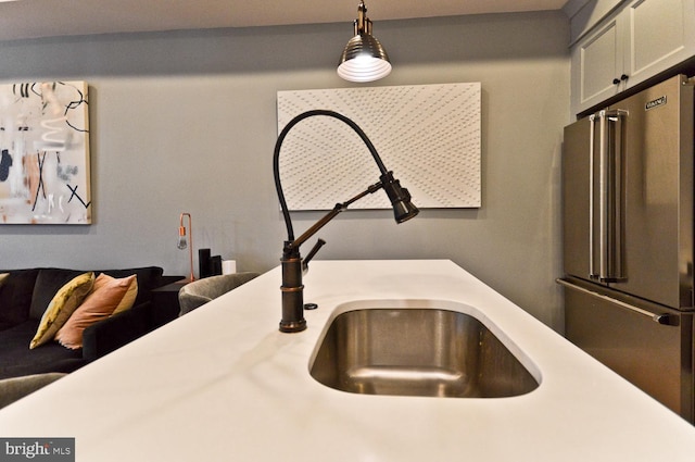 interior space with a sink, light countertops, high end fridge, and hanging light fixtures