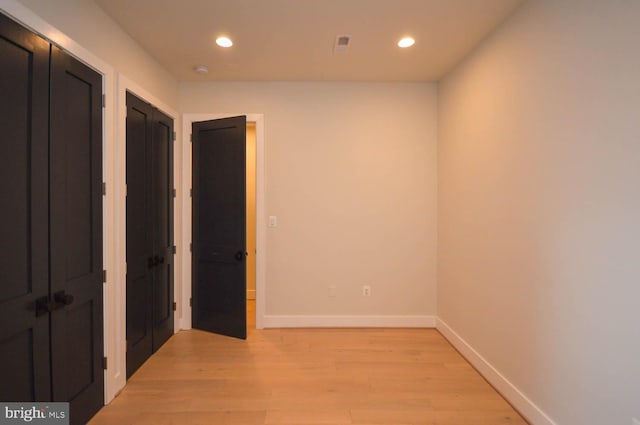 hallway featuring baseboards, recessed lighting, and light wood-style floors