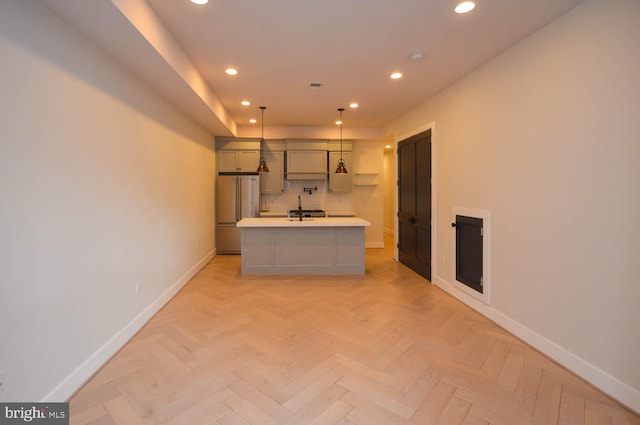 kitchen featuring high end fridge, recessed lighting, light countertops, a kitchen island with sink, and baseboards