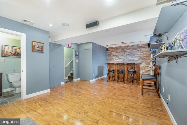 interior space with a dry bar, visible vents, track lighting, wood finished floors, and stairs