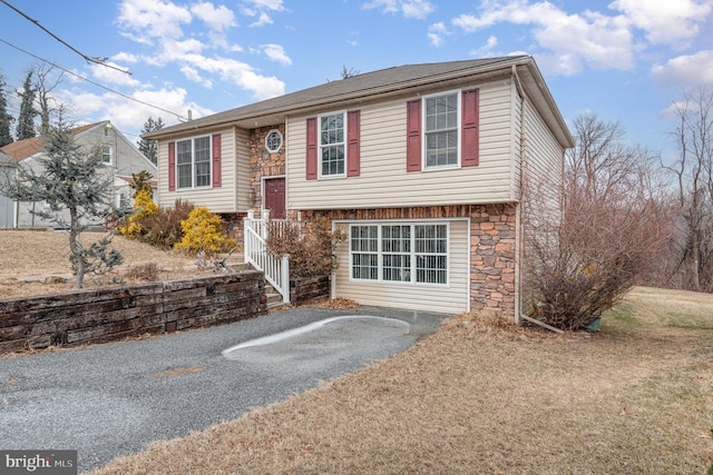 raised ranch with driveway and stone siding