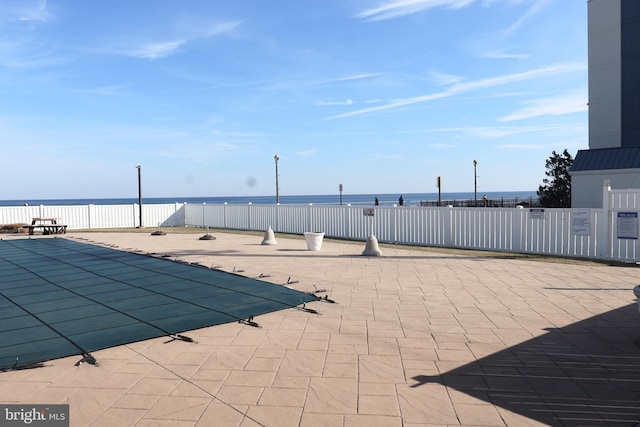 view of swimming pool featuring a patio area, a water view, and fence