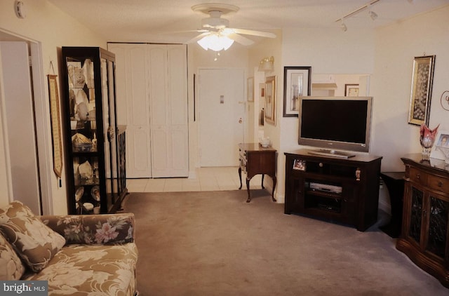 living room featuring ceiling fan, light tile patterned floors, track lighting, and light colored carpet