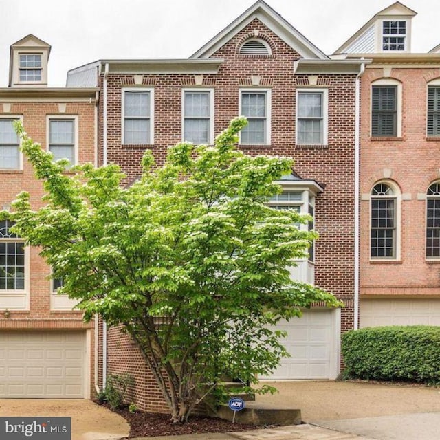 townhome / multi-family property featuring driveway, a garage, and brick siding