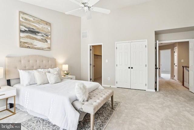 bedroom with ceiling fan, light carpet, a high ceiling, visible vents, and baseboards