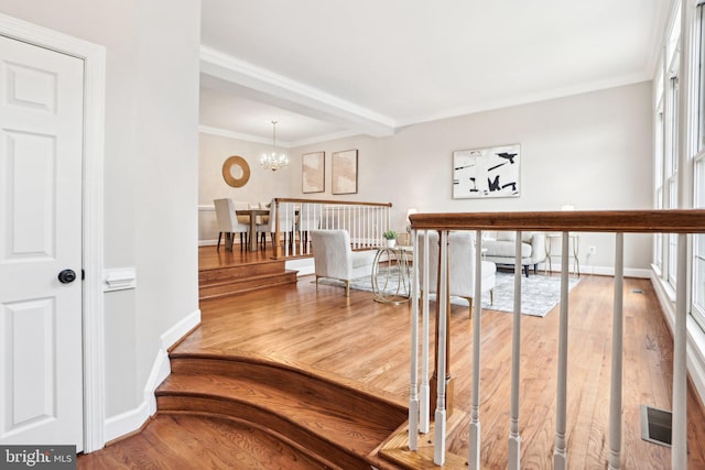 hall featuring ornamental molding, visible vents, a notable chandelier, and wood finished floors