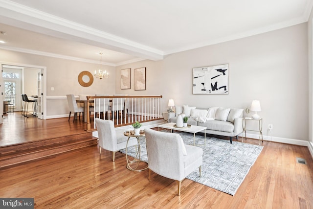 living area featuring visible vents, baseboards, wood finished floors, an inviting chandelier, and crown molding