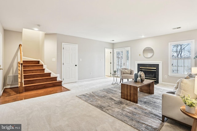 living room featuring carpet floors, visible vents, stairway, a high end fireplace, and baseboards