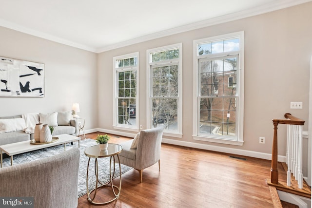 living area featuring light wood-type flooring, baseboards, ornamental molding, and a wealth of natural light