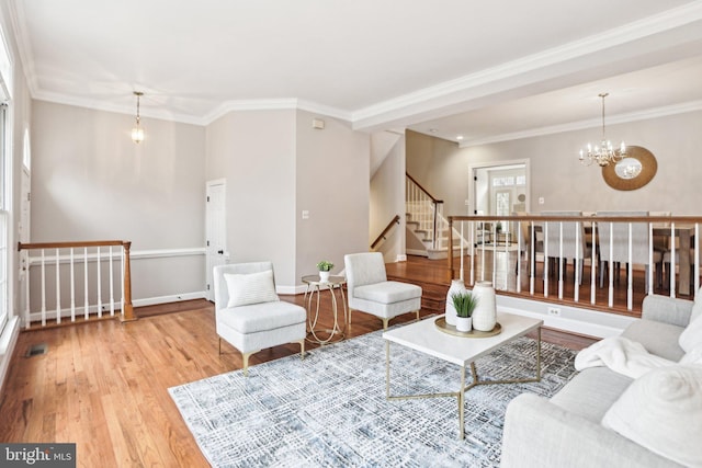 living room featuring light wood-style flooring, baseboards, stairs, an inviting chandelier, and crown molding