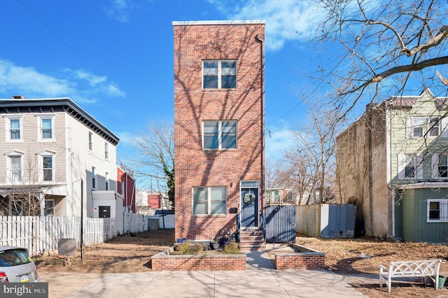 view of front of property featuring fence and brick siding