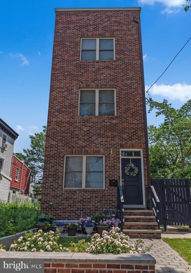 view of front of property with entry steps, fence, and brick siding