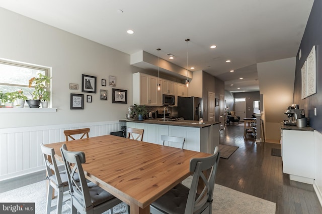 dining space with a wainscoted wall, dark wood-style floors, and recessed lighting