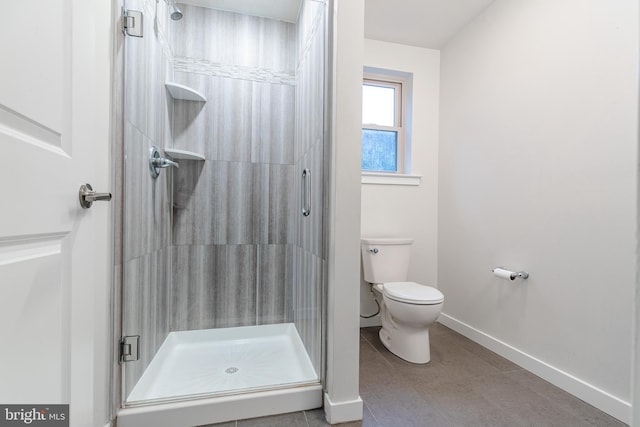 bathroom featuring baseboards, a shower stall, and toilet