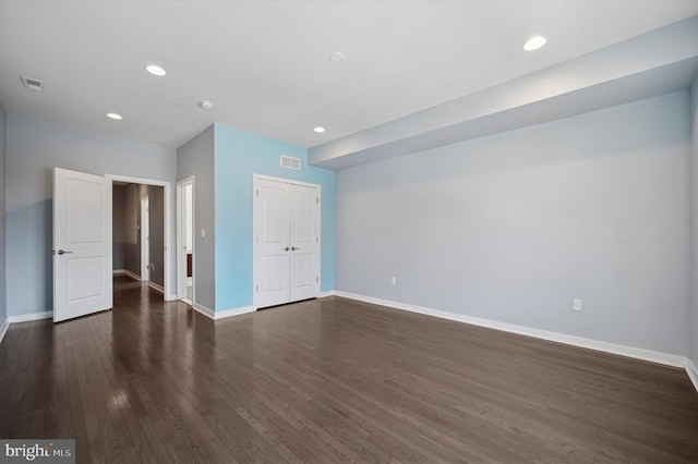 unfurnished bedroom with dark wood-style flooring, a closet, visible vents, and baseboards