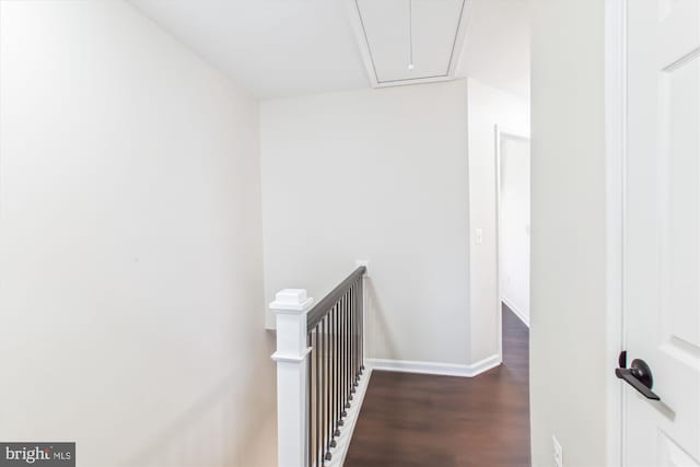 hall featuring wood finished floors, an upstairs landing, attic access, and baseboards