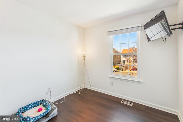 spare room featuring dark wood-style floors, visible vents, and baseboards