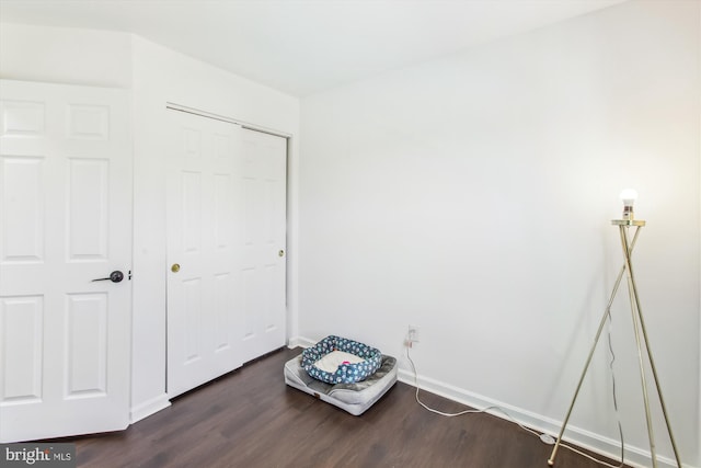 unfurnished bedroom featuring dark wood-style floors, baseboards, and a closet